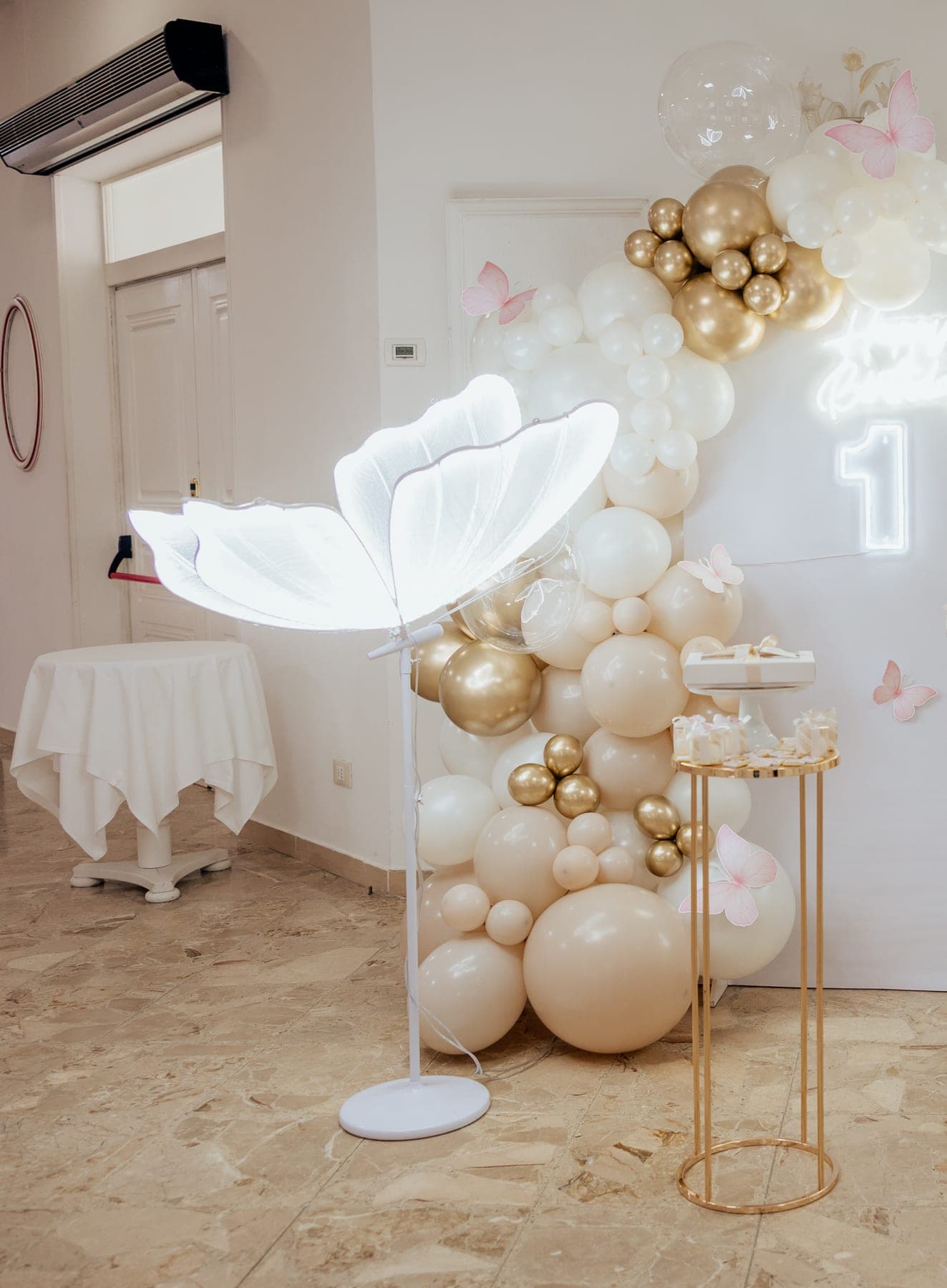 Arco di palloncini bianchi e oro con insegna luminosa, allestito per una festa